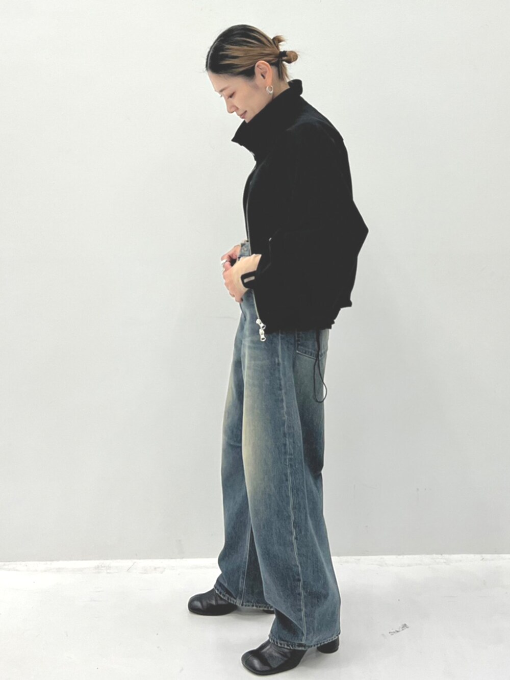 ベージュ系のTシャツ/カットソー、ブラック系のブルゾン、ブルー系のデニムパンツを着用したレディースの秋コーディネートの2枚目の写真