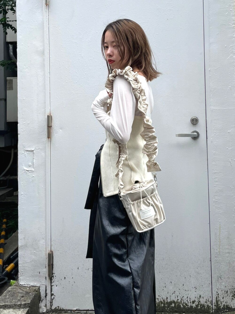 ブラック系のスカート、ベージュ系のショルダーバッグ、ホワイト系のTシャツ/カットソーを着用したレディースの秋コーディネートの3枚目の写真