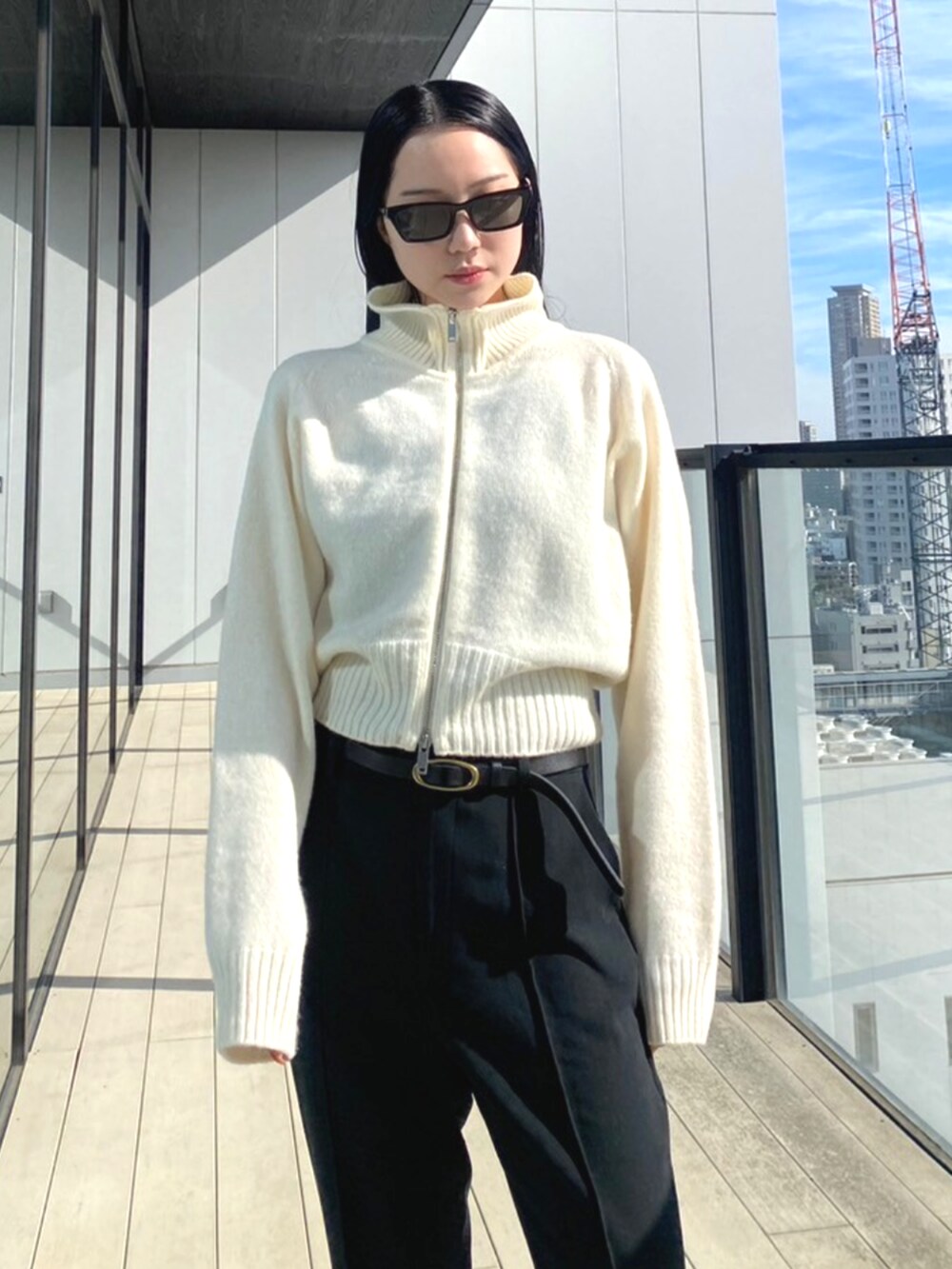 ブラック系のスラックス、ホワイト系のニット/セーターを着用したレディースの秋コーディネートの4枚目の写真