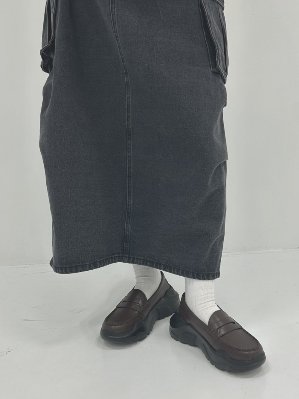 ブラック系のデニムスカート、グリーン系のブルゾン、ブラウン系のローファーを着用したレディースの春コーディネートの3枚目の写真