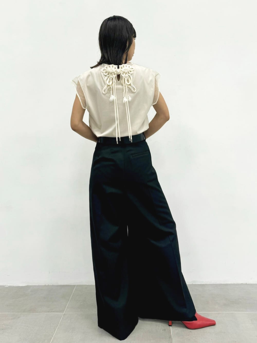 ブラック系のスラックス、ベージュ系のTシャツ/カットソー、シルバー系のイヤリングを着用したレディースの夏コーディネートの3枚目の写真