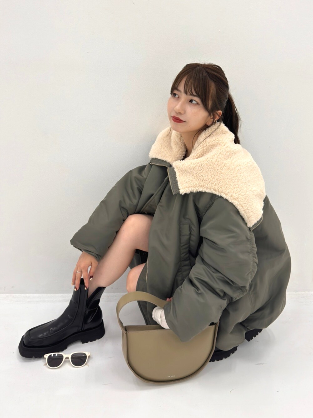 グリーン系のブルゾン、グレー系のハンドバッグを着用したレディースの秋コーディネートの4枚目の写真