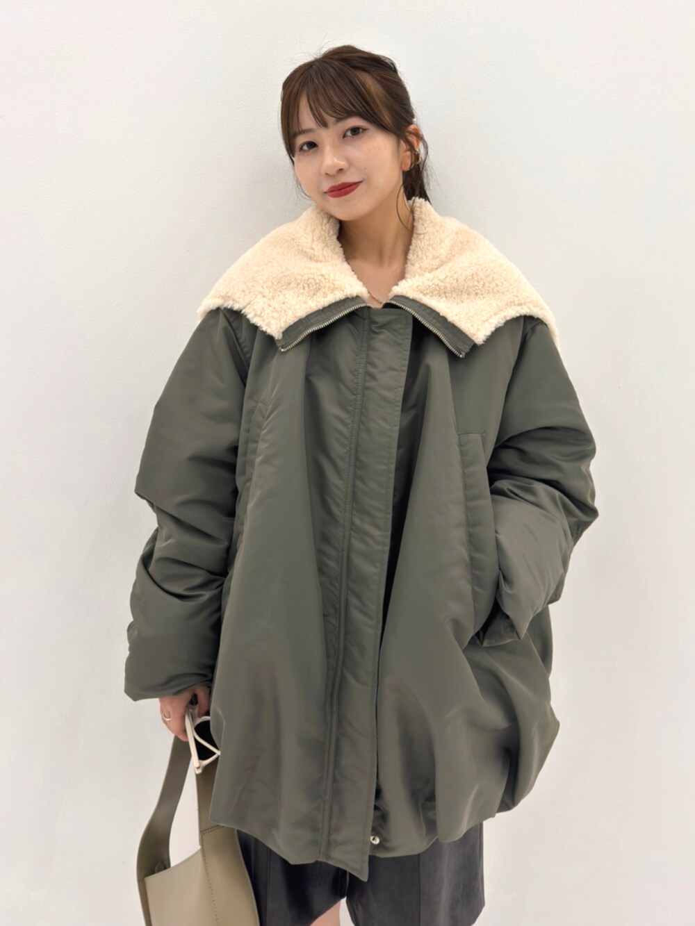 グリーン系のブルゾン、グレー系のハンドバッグを着用したレディースの秋コーディネートの3枚目の写真