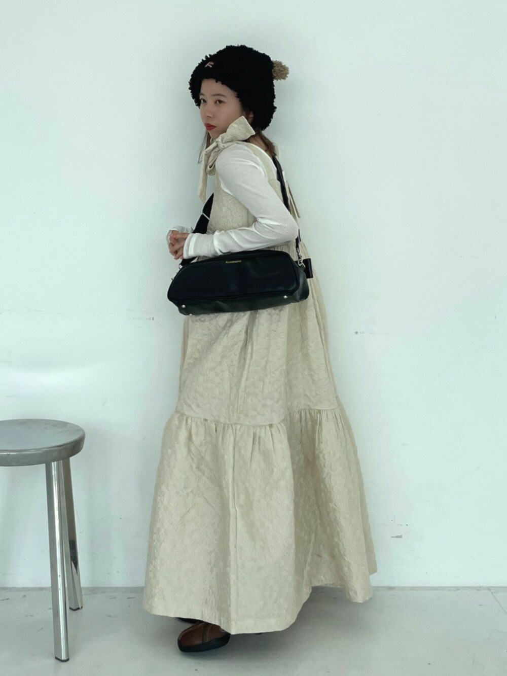 ブラック系のショルダーバッグ、ブラウン系のバレエシューズ、ホワイト系のワンピースを着用したレディースの秋コーディネートの2枚目の写真