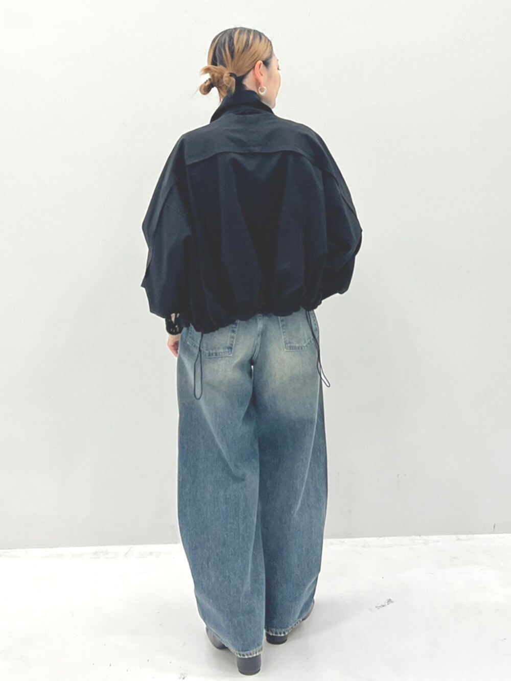 ベージュ系のTシャツ/カットソー、ブラック系のブルゾン、ブルー系のデニムパンツを着用したレディースの秋コーディネートの3枚目の写真