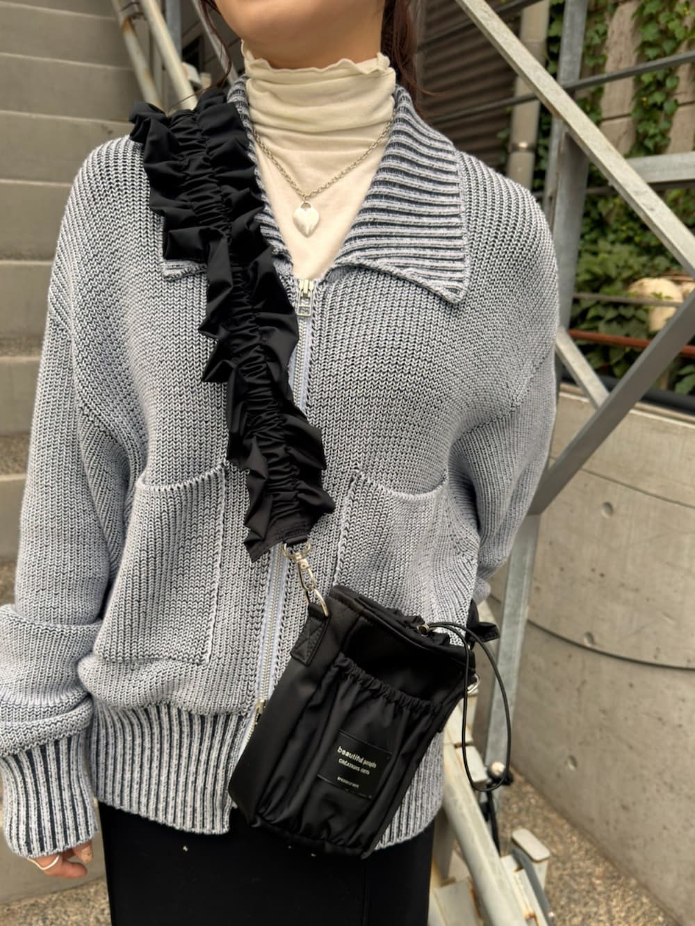 ブルー系のニット/セーター、ブラック系のショルダーバッグ、ブラック系のスカートを着用したレディースの秋コーディネートの3枚目の写真