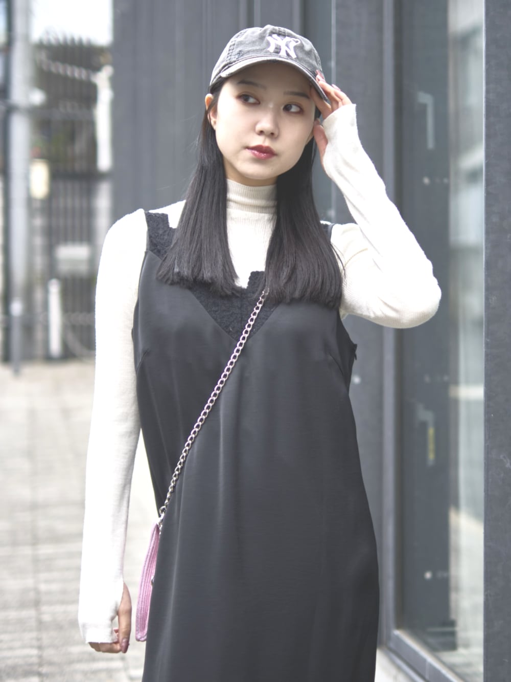 ブラック系のドレス、ピンク系のショルダーバッグ、ブラック系のキャップを着用したレディースの冬コーディネートの6枚目の写真