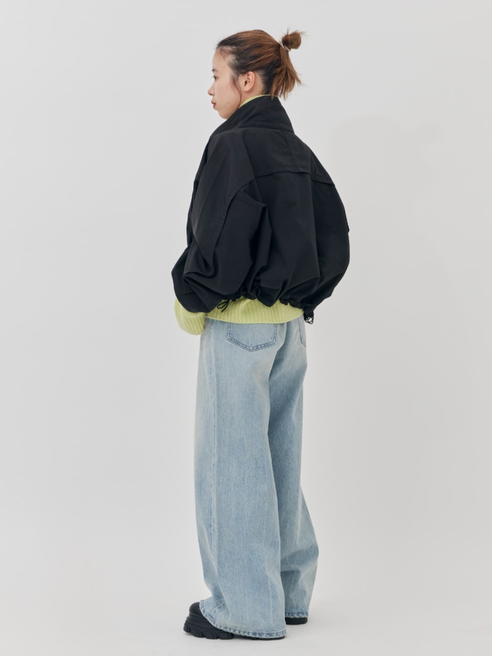 ブラック系のブルゾン、ブルー系のデニムパンツ、グリーン系のニット/セーターを着用したレディースの秋コーディネートの3枚目の写真