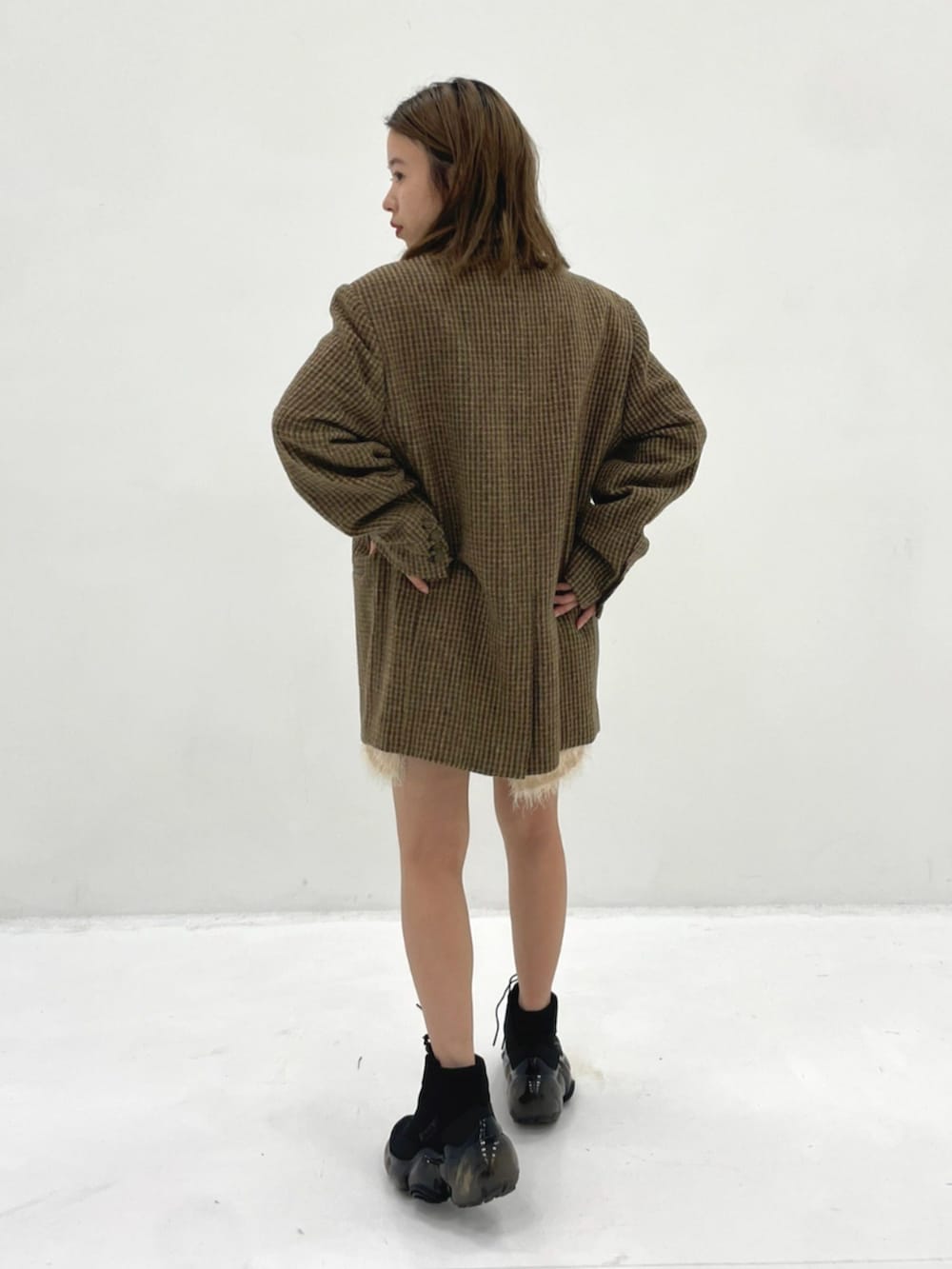 イエロー系のテーラードジャケット、ブラック系のスニーカーを着用したレディースの秋コーディネートの2枚目の写真