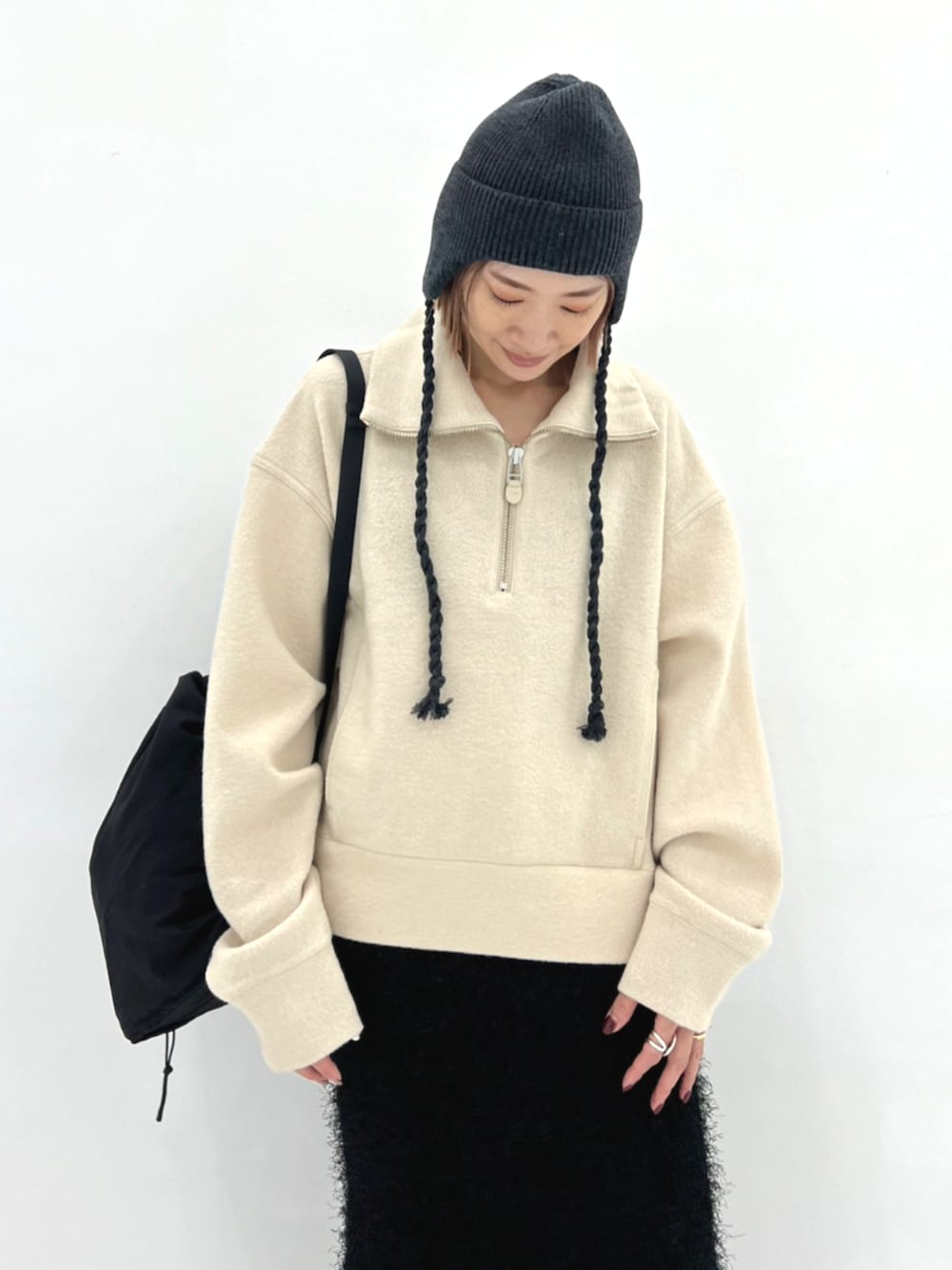 ベージュ系のニット/セーター、ブラック系のバックパック/リュック、グレー系のニットキャップ/ビーニーを着用したレディースの秋コーディネートの3枚目の写真