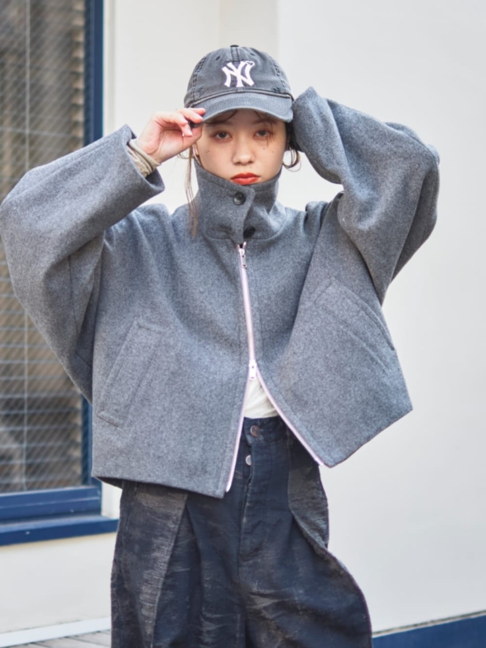 グレー系のブルゾン、グリーン系のショルダーバッグ、ブラック系のキャップを着用したレディースの冬コーディネートの2枚目の写真