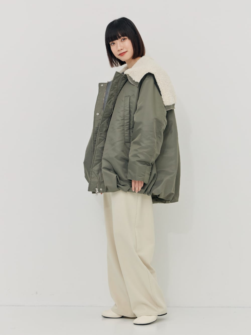 グリーン系のブルゾン、ホワイト系のその他パンツを着用したレディースの秋コーディネートの2枚目の写真