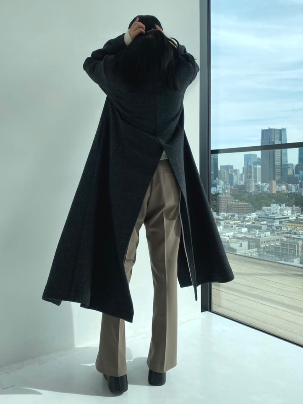 グレー系のチェスターコート、ホワイト系のニット/セーター、グレー系のスラックスを着用したレディースの秋コーディネートの5枚目の写真