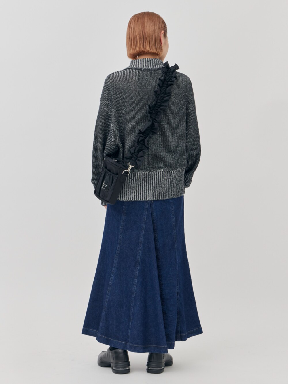 ブラック系のニット/セーター、ブラック系のショルダーバッグ、ブルー系のスカートを着用したレディースの秋コーディネートの4枚目の写真