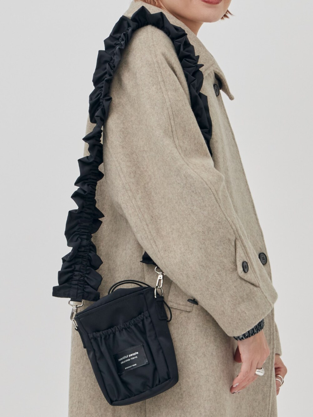 ブラック系のショルダーバッグ、ベージュ系のその他アウターを着用したレディースの秋コーディネートの4枚目の写真