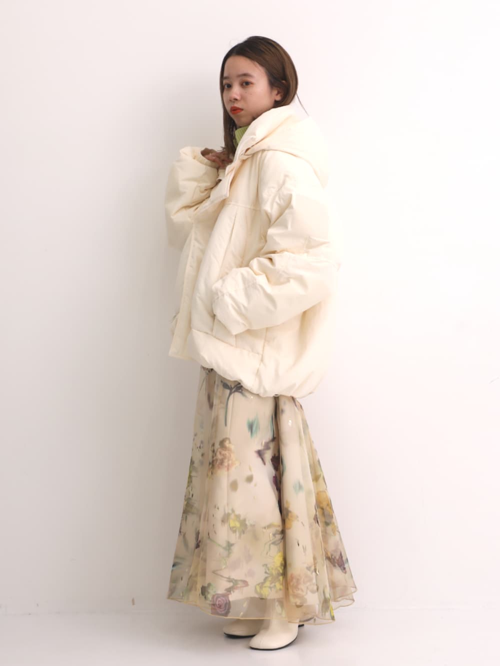 グリーン系のニット/セーター、ホワイト系のダウンジャケット/コートを着用したレディースの秋コーディネートの2枚目の写真