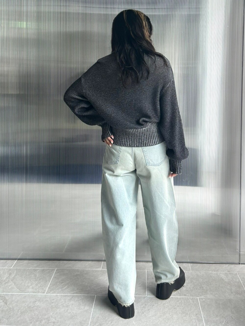 ブルー系のデニムパンツ、ブラック系のニット/セーター、ブラック系のスリッポンを着用したレディースの秋コーディネートの2枚目の写真