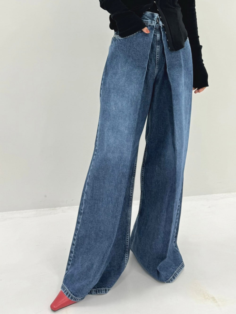 ブルー系のデニムパンツ、レッド系のハンドバッグ、ブラック系のポロシャツを着用したレディースの秋コーディネートの4枚目の写真