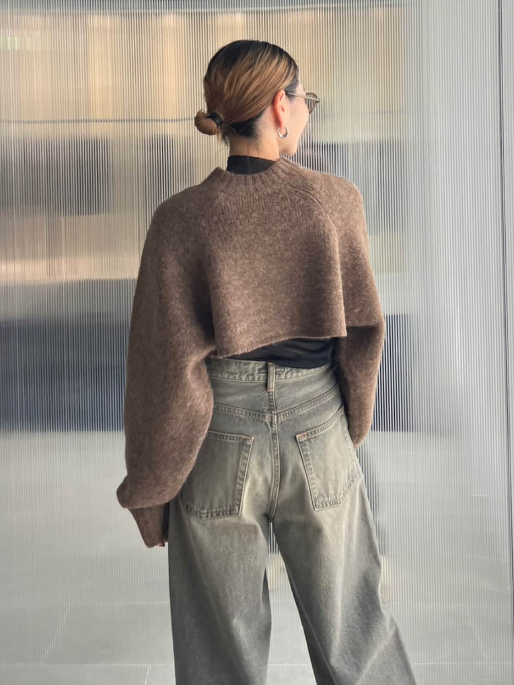 ブラック系のデニムパンツ、ベージュ系のスリッポン、ブラウン系のカーディガン/ボレロを着用したレディースの秋コーディネートの3枚目の写真