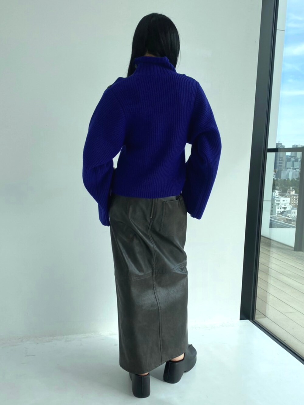 グレー系のスカート、ブルー系のニット/セーターを着用したレディースの秋コーディネートの2枚目の写真