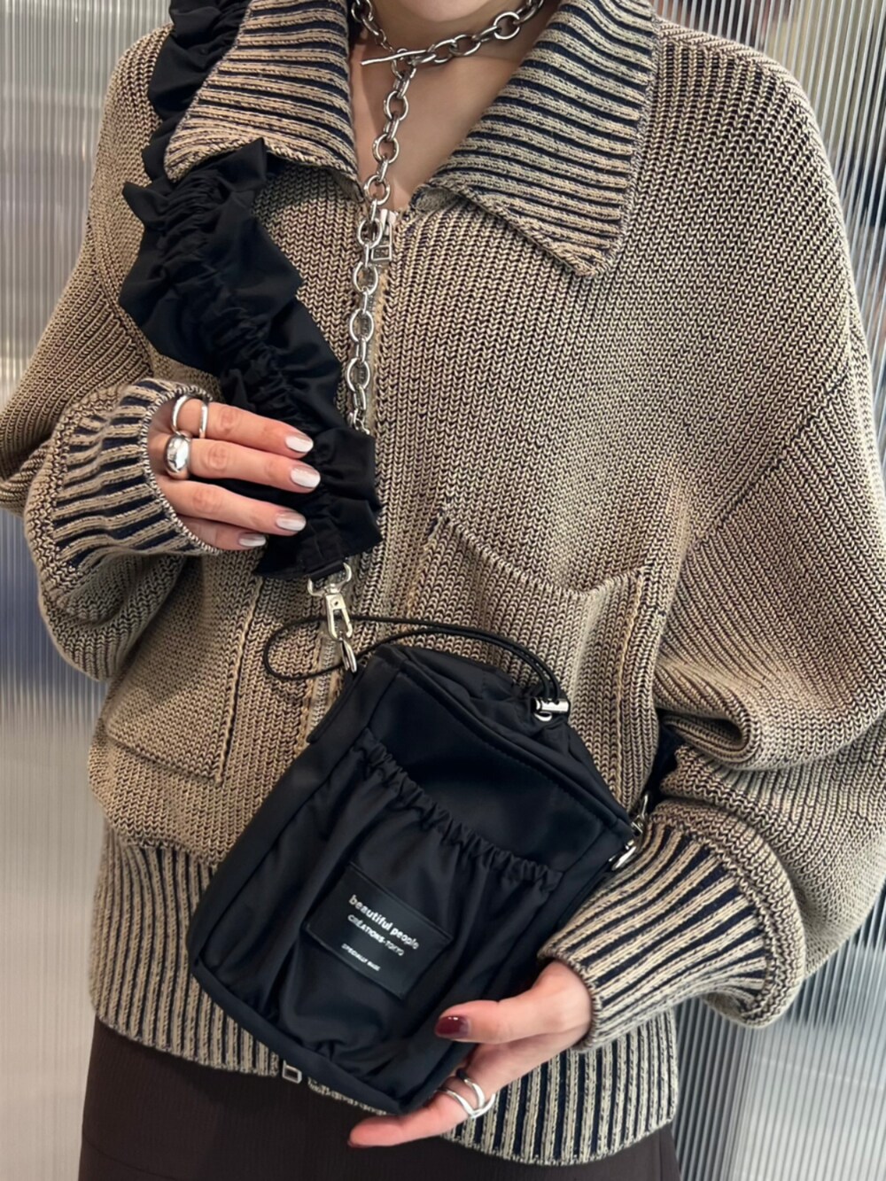 グリーン系のニット/セーター、ブラック系のショルダーバッグを着用したレディースの秋コーディネートの4枚目の写真