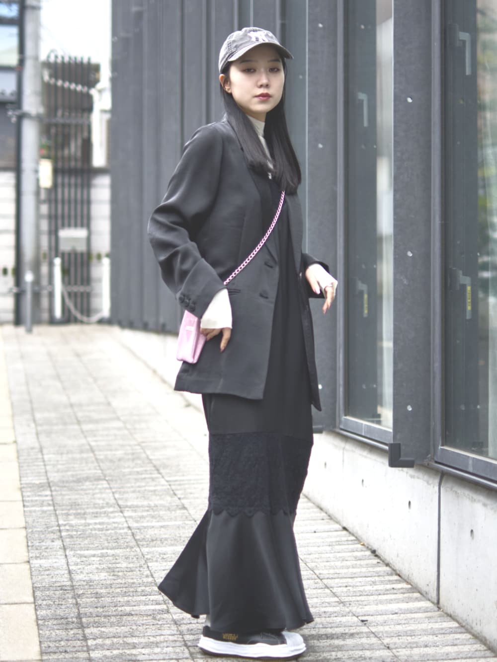 ブラック系のドレス、ピンク系のショルダーバッグ、ブラック系のキャップを着用したレディースの冬コーディネートの2枚目の写真