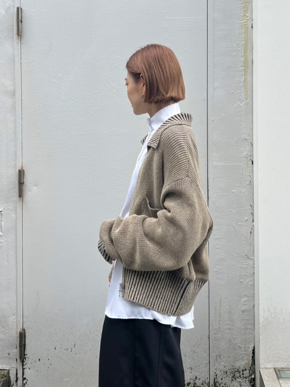 ブラック系のスラックス、グリーン系のニット/セーター、ホワイト系のシャツ/ブラウスを着用したレディースの秋コーディネートの3枚目の写真