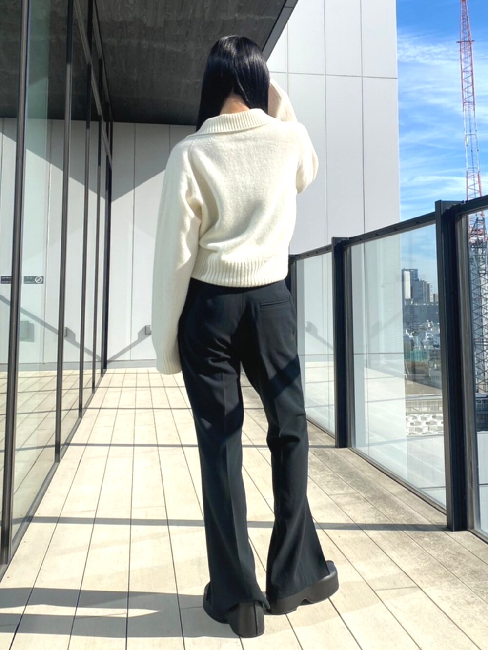ブラック系のスラックス、ホワイト系のニット/セーターを着用したレディースの秋コーディネートの3枚目の写真