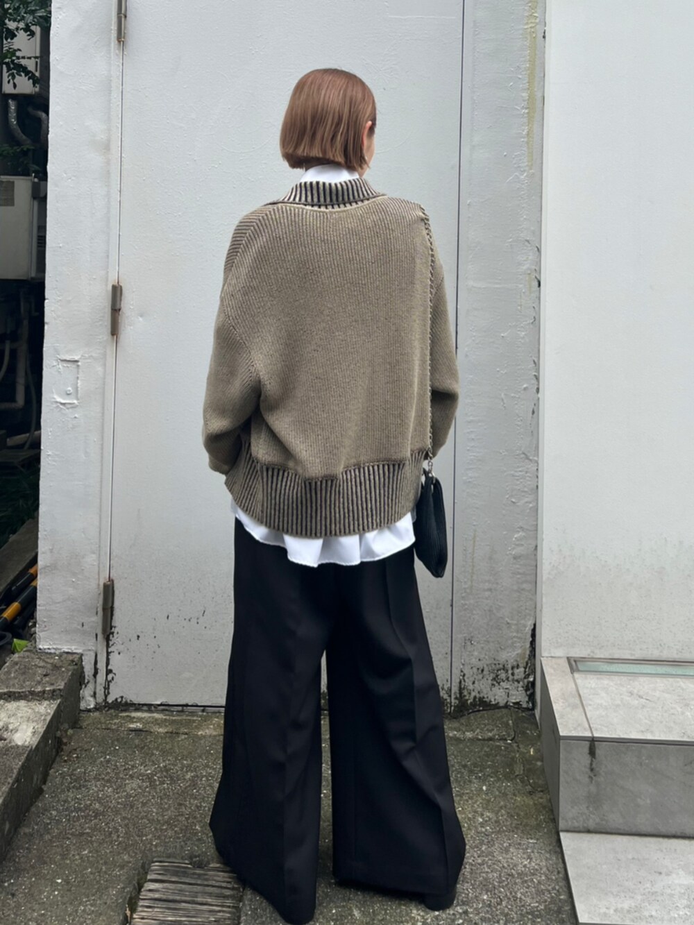 ブラック系のスラックス、グリーン系のニット/セーター、ホワイト系のシャツ/ブラウスを着用したレディースの秋コーディネートの2枚目の写真