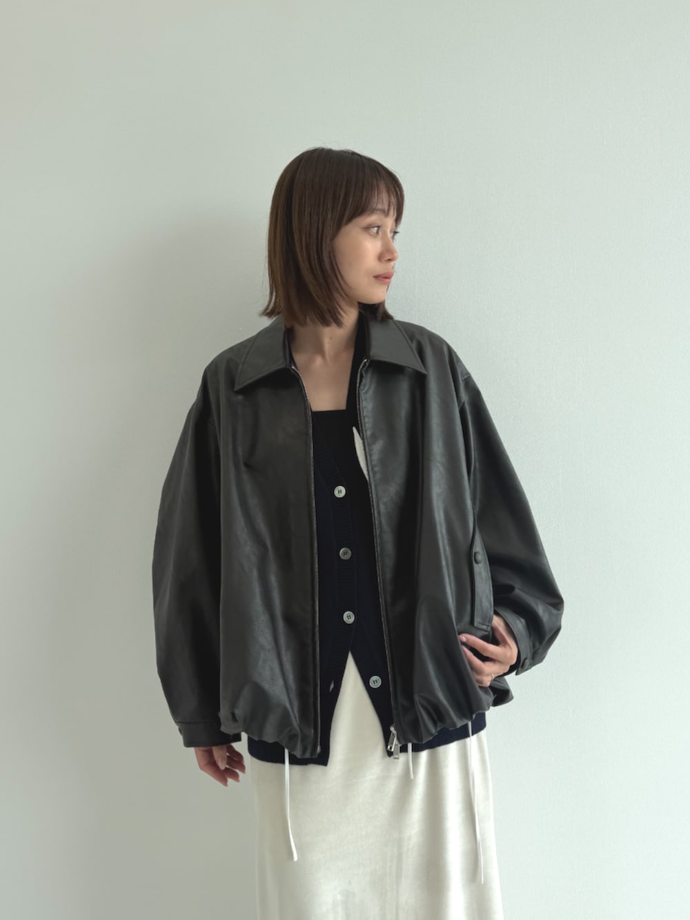 ブルー系のカーディガン/ボレロ、ブラック系のライダースジャケット、ベージュ系のスカートを着用したレディースの秋コーディネートの4枚目の写真