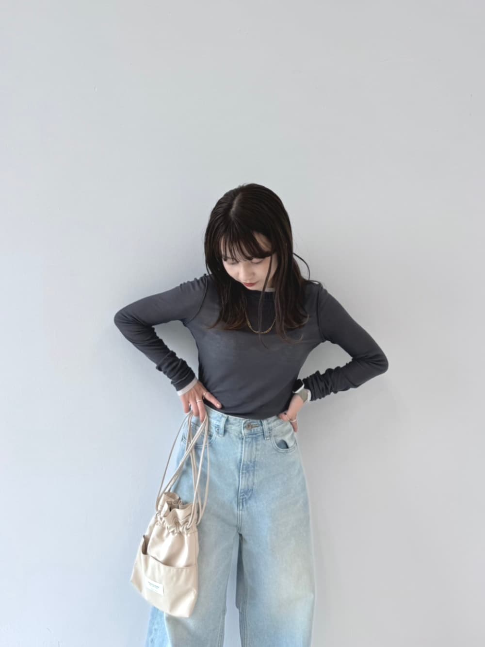 ブルー系のデニムパンツ、ベージュ系のショルダーバッグを着用したレディースの秋コーディネートの2枚目の写真