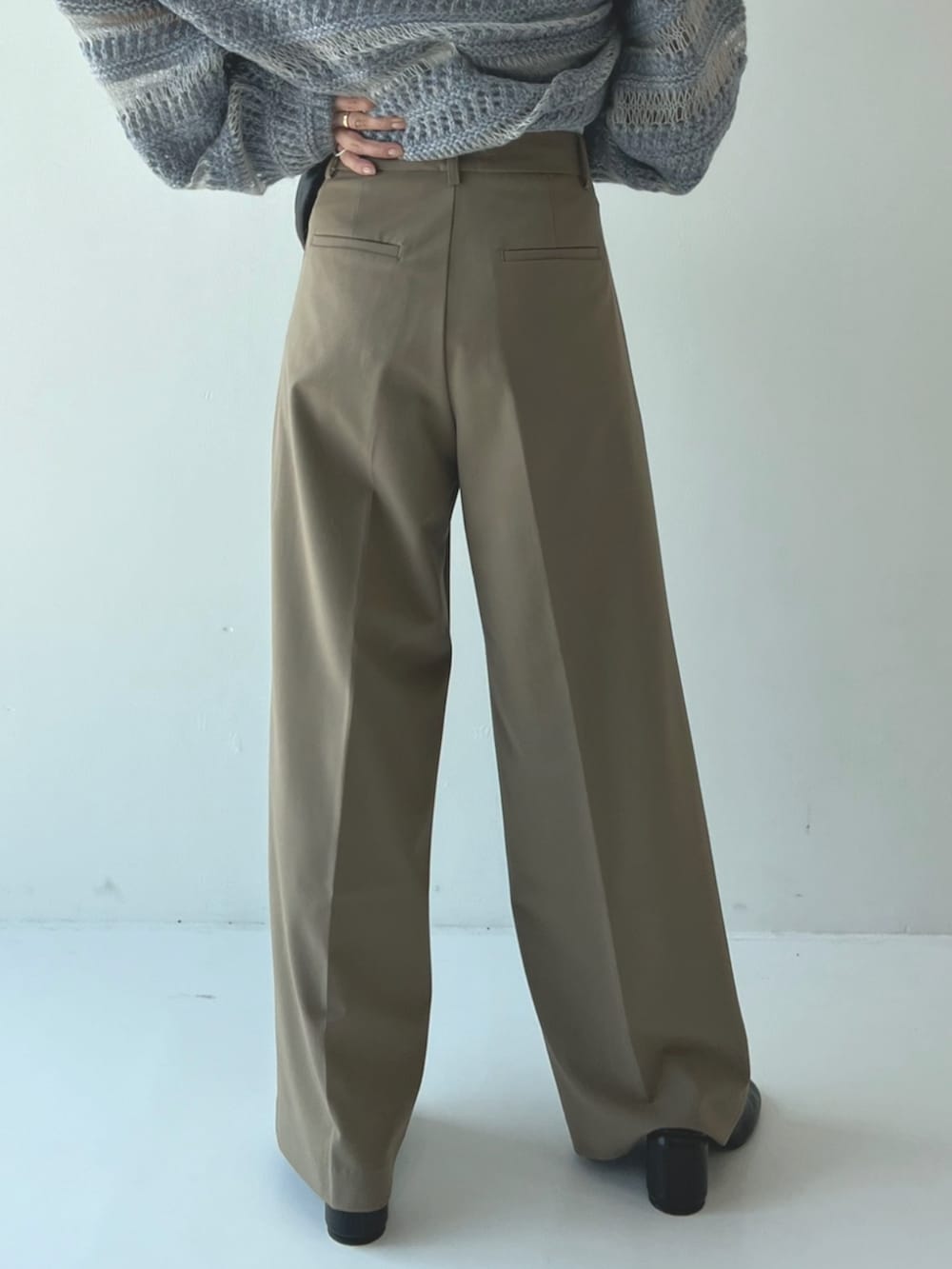 ブルー系のニット/セーター、ブラック系のハンドバッグ、グリーン系のスラックスを着用したレディースの秋コーディネートの3枚目の写真