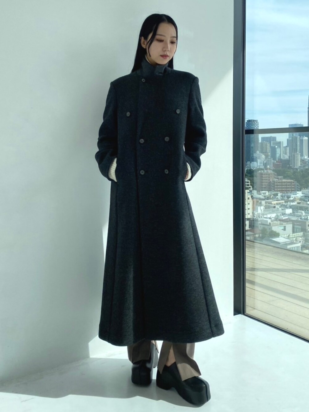 グレー系のチェスターコート、ホワイト系のニット/セーター、グレー系のスラックスを着用したレディースの秋コーディネートの4枚目の写真