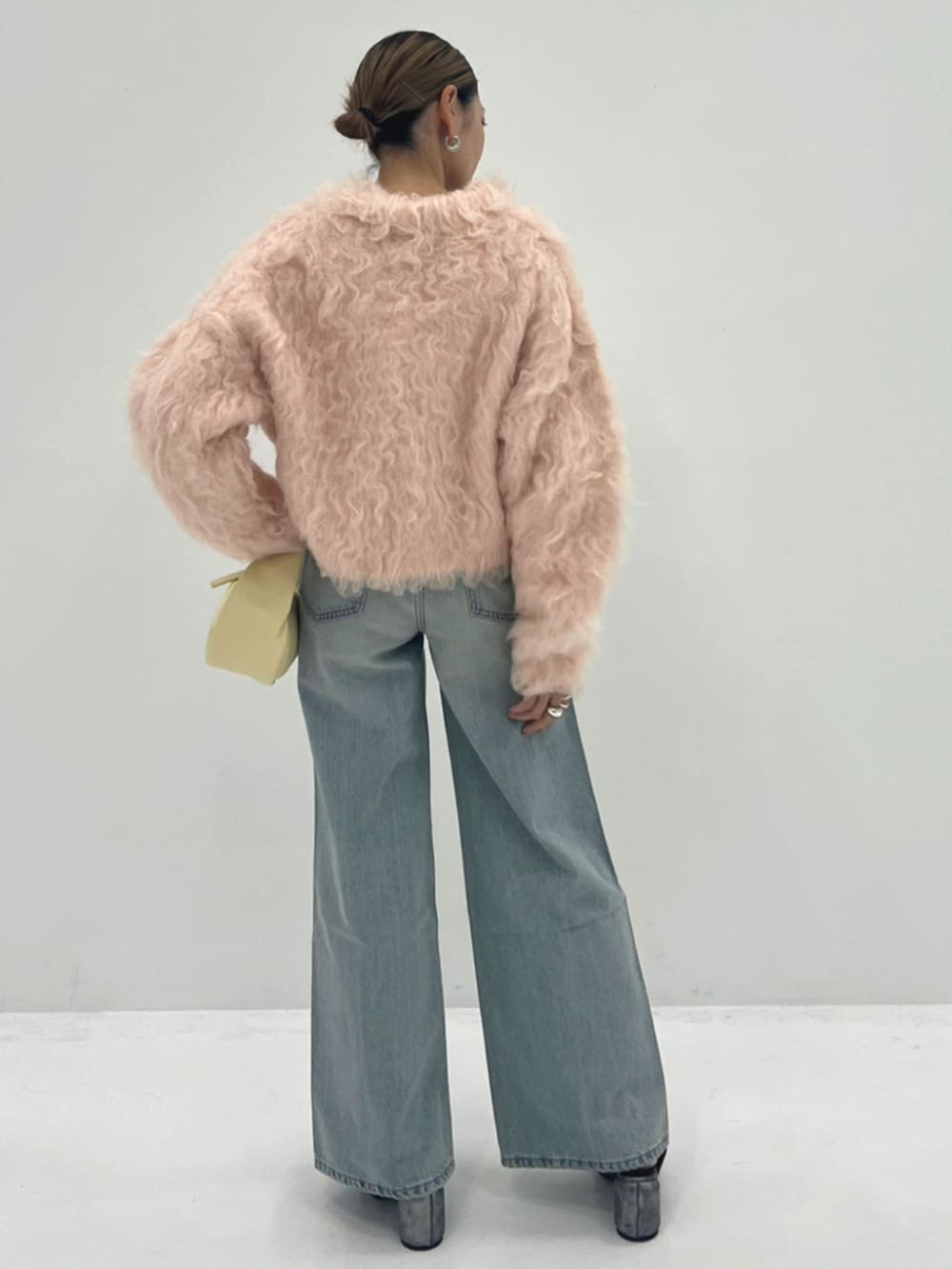 ベージュ系のハンドバッグ、ピンク系のカーディガン/ボレロ、ブルー系のデニムパンツを着用したレディースの秋コーディネートの2枚目の写真