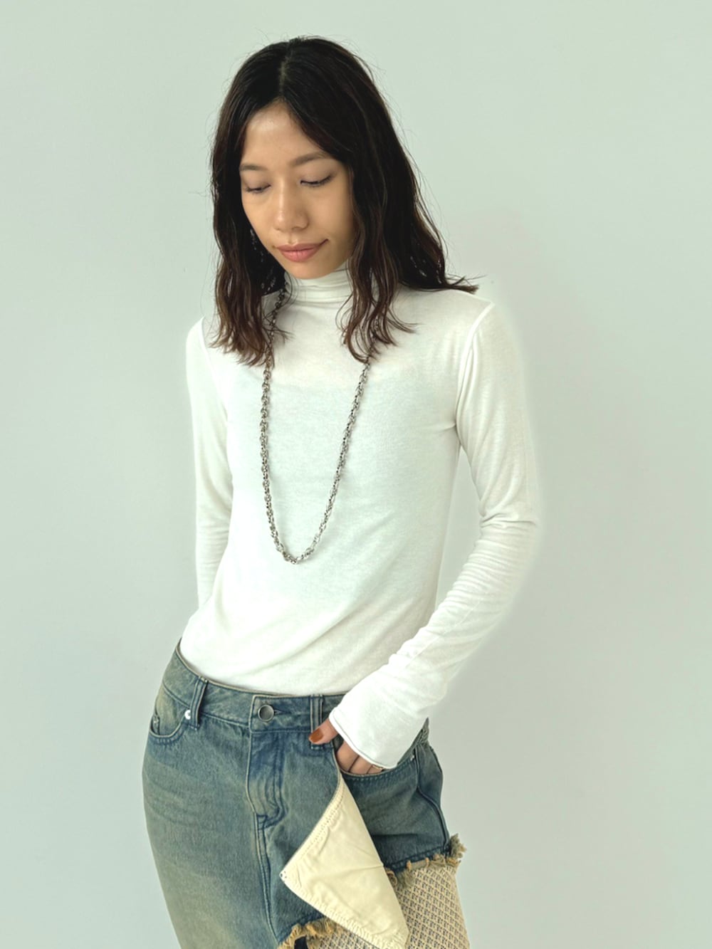 ブラック系のブルゾン、ホワイト系のTシャツ/カットソー、ベージュ系のデニムスカートを着用したレディースの秋コーディネートの2枚目の写真