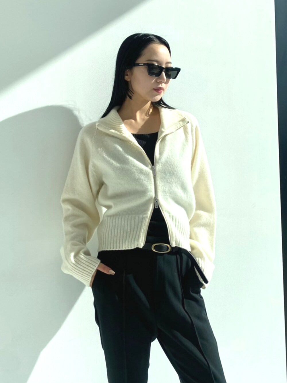 ブラック系のスラックス、ホワイト系のニット/セーターを着用したレディースの秋コーディネートの6枚目の写真