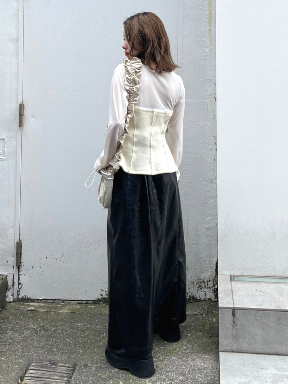 ブラック系のスカート、ベージュ系のショルダーバッグ、ホワイト系のTシャツ/カットソーを着用したレディースの秋コーディネートの2枚目の写真