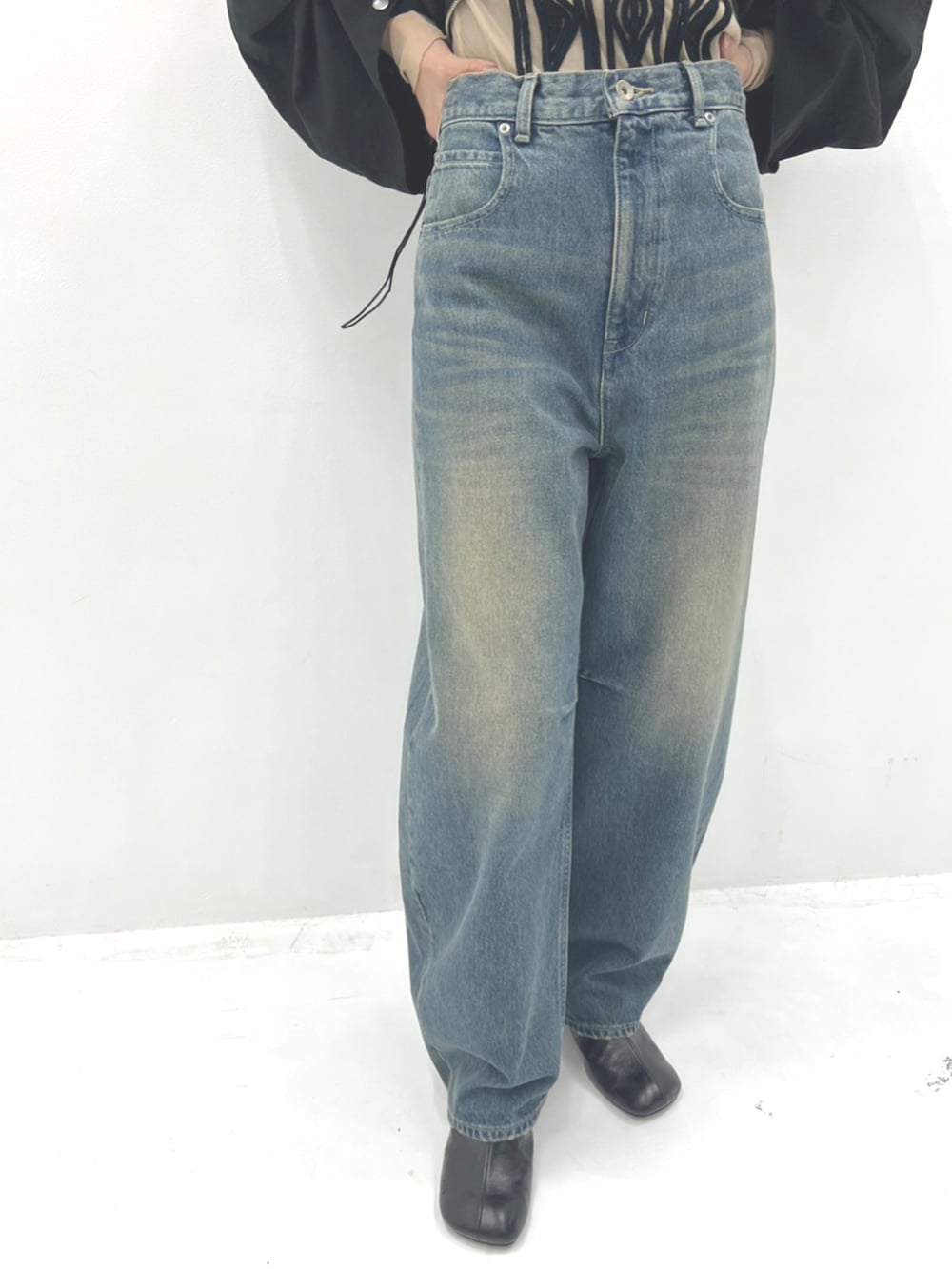 ベージュ系のTシャツ/カットソー、ブラック系のブルゾン、ブルー系のデニムパンツを着用したレディースの秋コーディネートの4枚目の写真