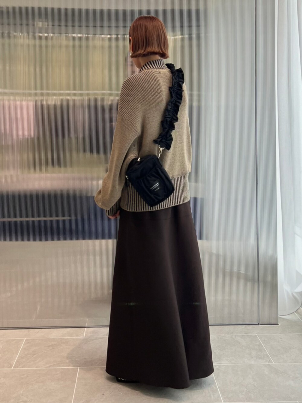 グリーン系のニット/セーター、ブラック系のショルダーバッグを着用したレディースの秋コーディネートの2枚目の写真