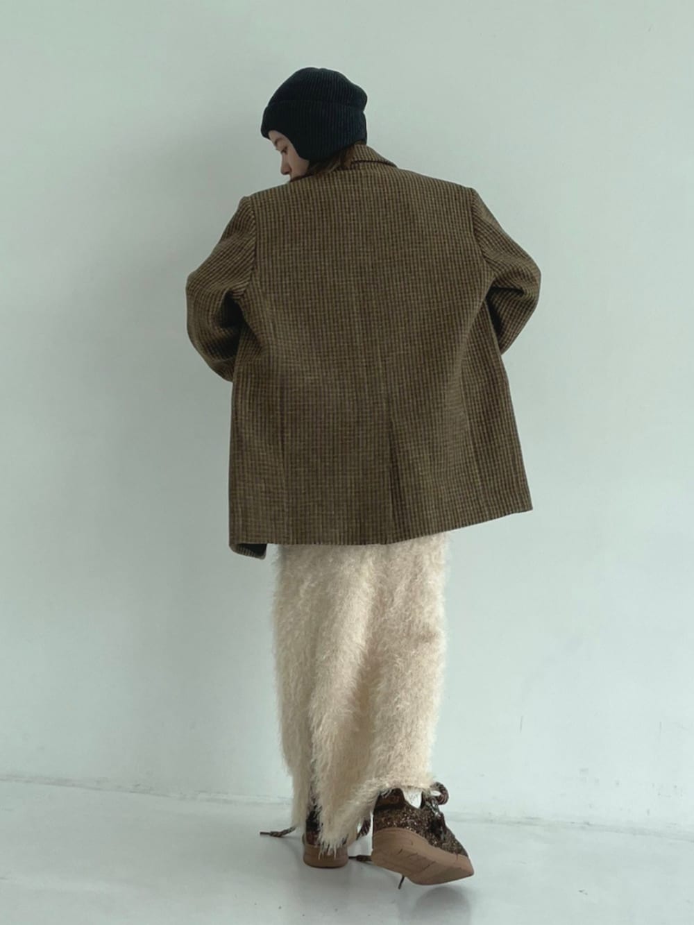 イエロー系のテーラードジャケット、ホワイト系のスカート、ブラウン系のスニーカーを着用したレディースの秋コーディネートの3枚目の写真