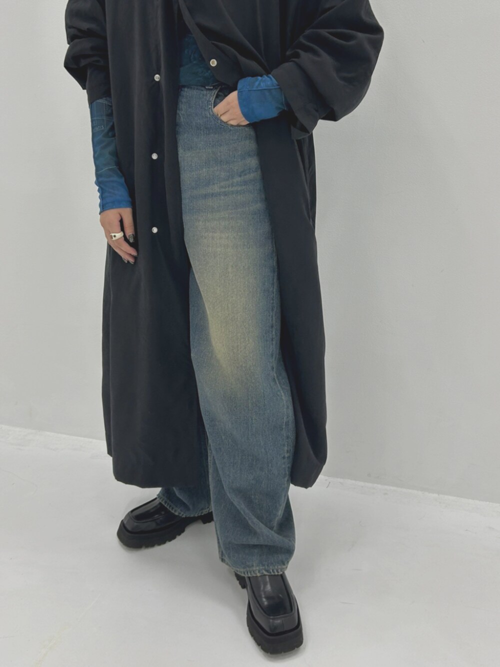 ブルー系のTシャツ/カットソー、ブラック系のステンカラーコート、ブルー系のデニムパンツを着用したレディースの秋コーディネートの4枚目の写真