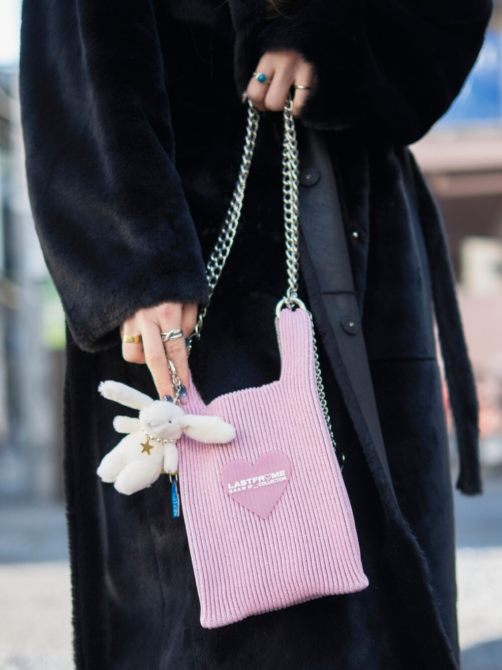 ピンク系のショルダーバッグ、ブラック系のピーコート、ブラック系のキャップを着用したレディースの冬コーディネートの4枚目の写真