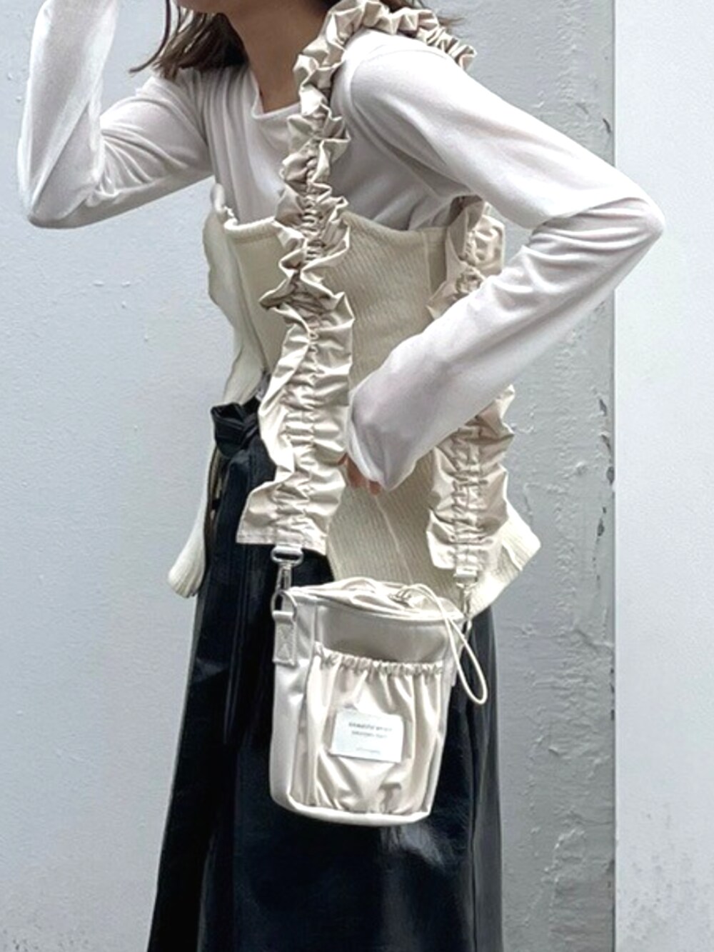 ブラック系のスカート、ベージュ系のショルダーバッグ、ホワイト系のTシャツ/カットソーを着用したレディースの秋コーディネートの4枚目の写真