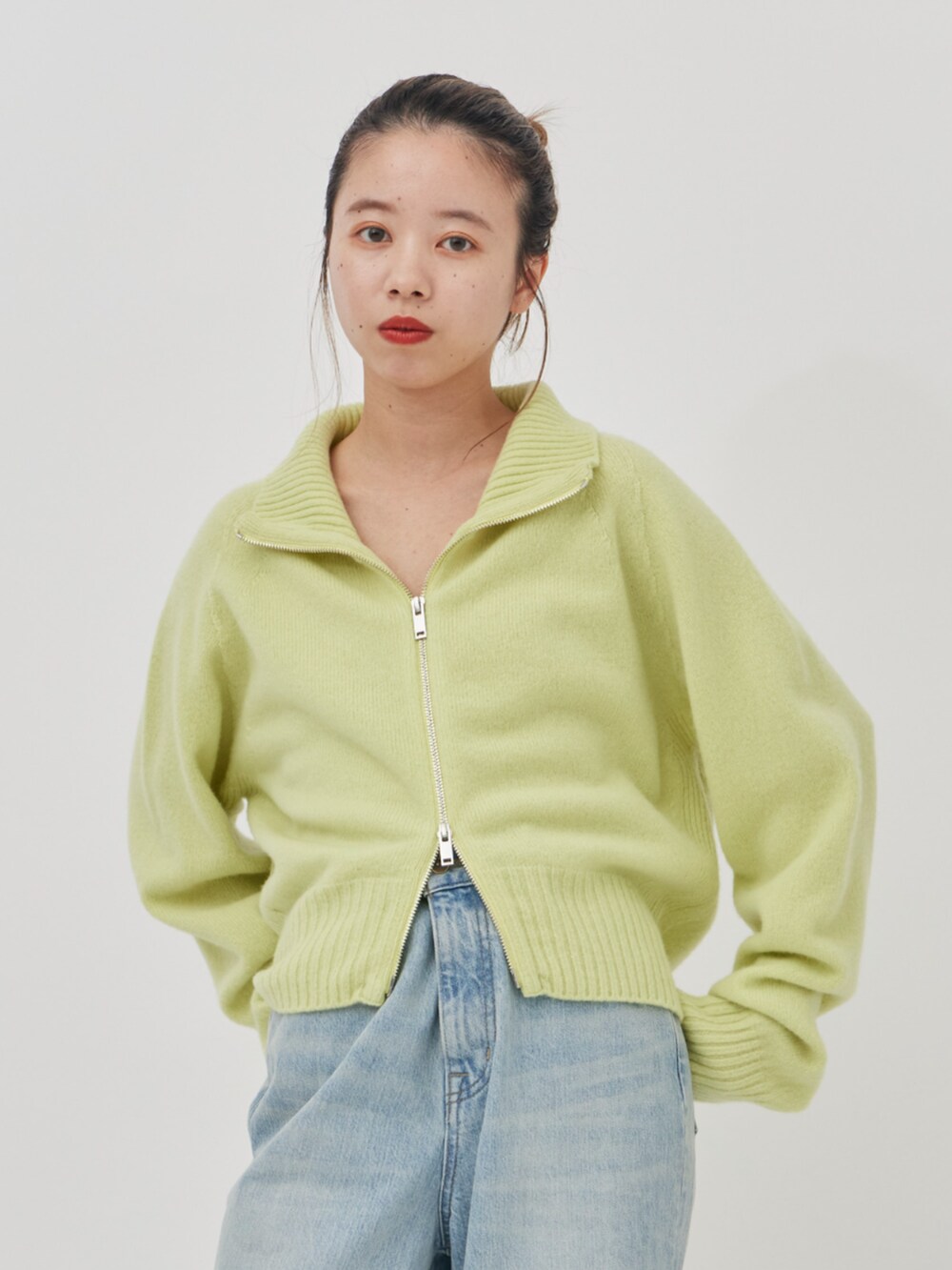 ブラック系のブルゾン、ブルー系のデニムパンツ、グリーン系のニット/セーターを着用したレディースの秋コーディネートの5枚目の写真