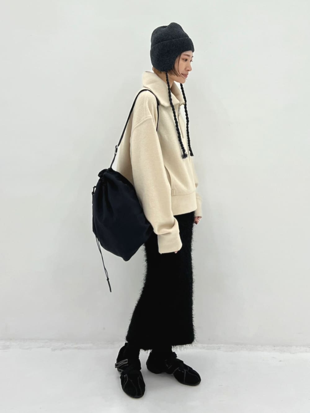 ベージュ系のニット/セーター、ブラック系のバックパック/リュック、グレー系のニットキャップ/ビーニーを着用したレディースの秋コーディネートの2枚目の写真