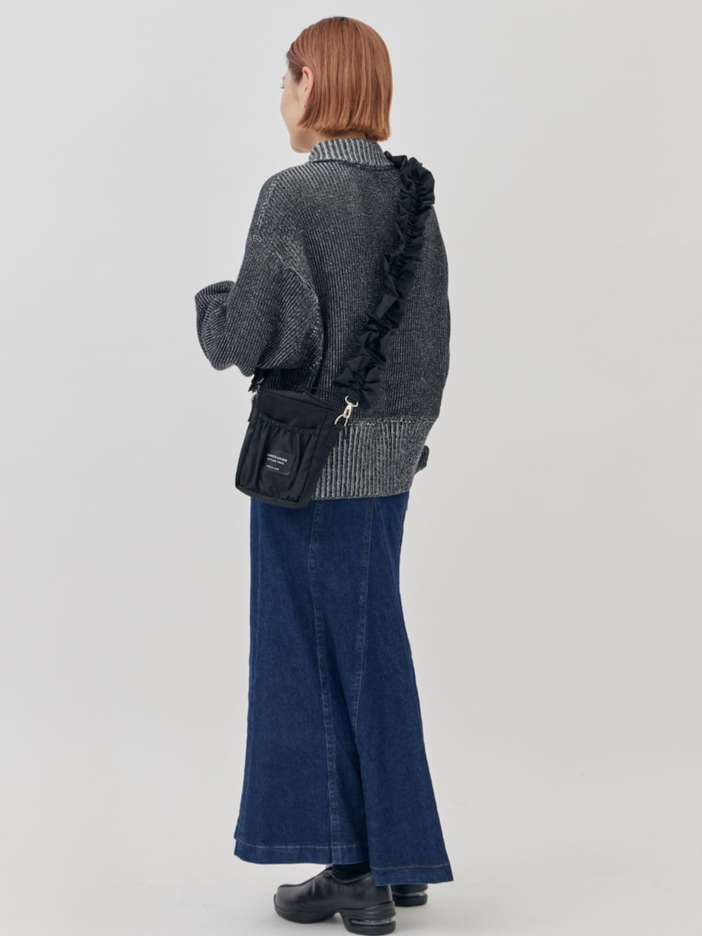 ブラック系のニット/セーター、ブラック系のショルダーバッグ、ブルー系のスカートを着用したレディースの秋コーディネートの3枚目の写真