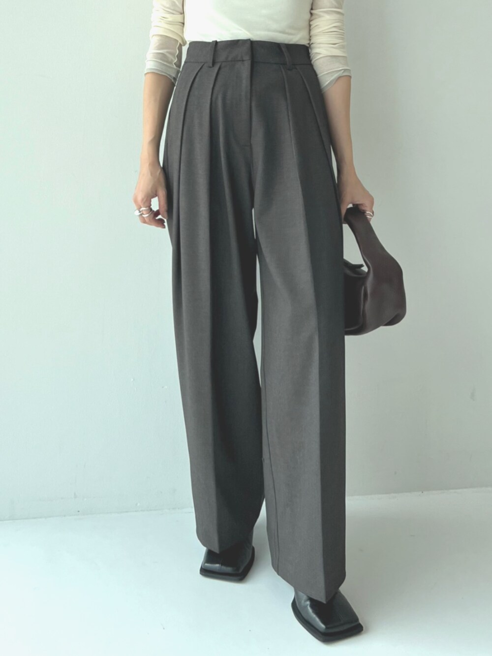 ブラック系のブーツ、ホワイト系のTシャツ/カットソー、グレー系のスラックスを着用したレディースの秋コーディネートの3枚目の写真