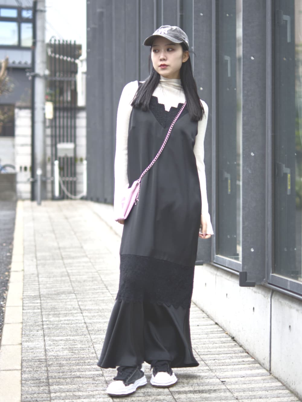 ブラック系のドレス、ピンク系のショルダーバッグ、ブラック系のキャップを着用したレディースの冬コーディネートの4枚目の写真