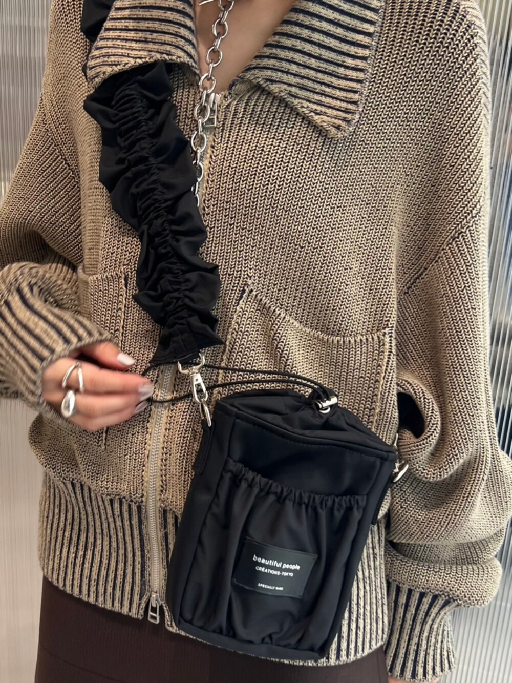 グリーン系のニット/セーター、ブラック系のショルダーバッグを着用したレディースの秋コーディネートの3枚目の写真