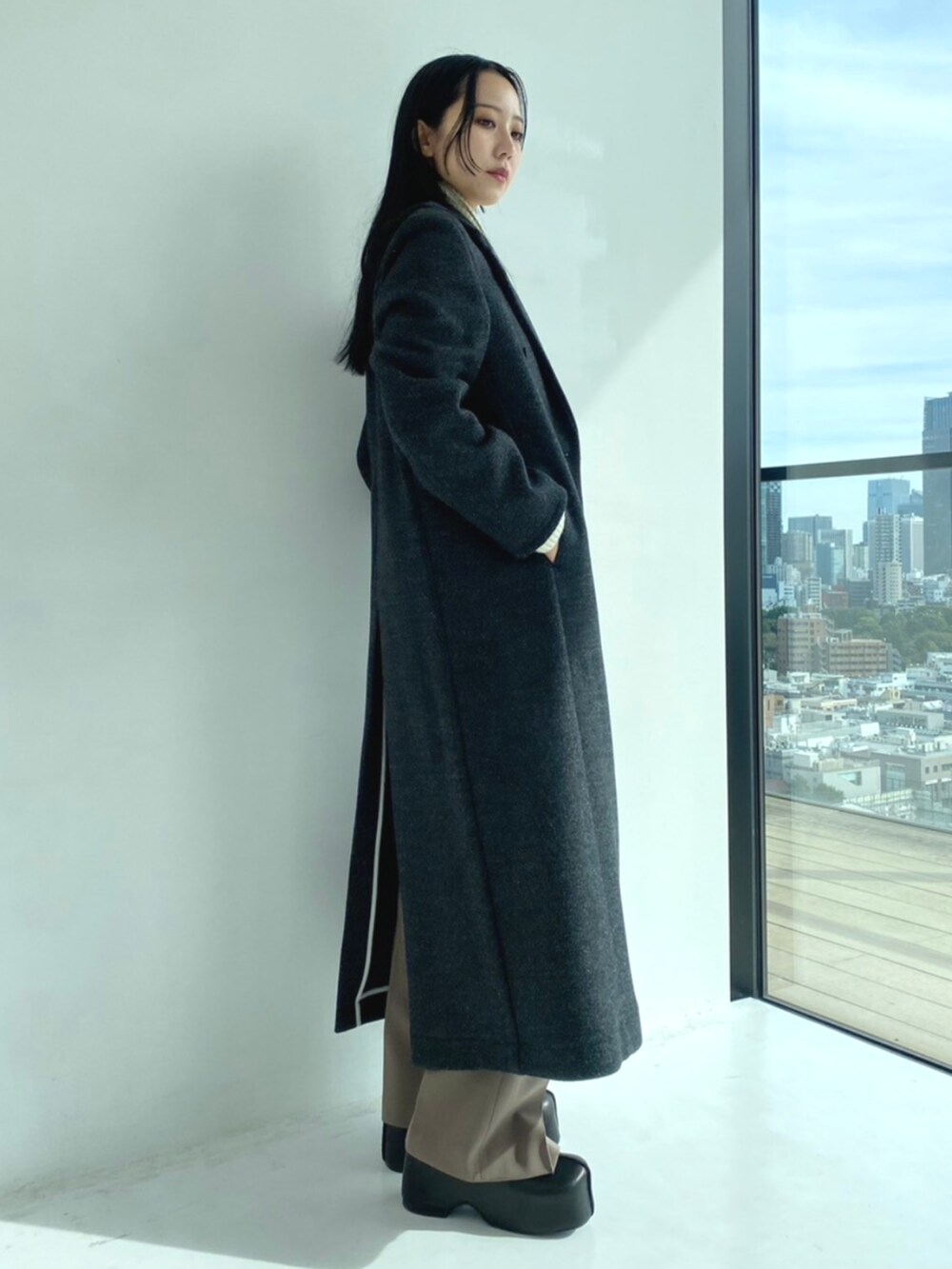 グレー系のチェスターコート、ホワイト系のニット/セーター、グレー系のスラックスを着用したレディースの秋コーディネートの3枚目の写真